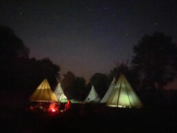 Tipi-Lager bei Nacht, Zelte bunt erleuchtet