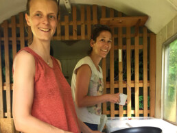 Trainerinnen Aline und Elena machen Abwasch im Küchenwagen des Tipi-Dorfes