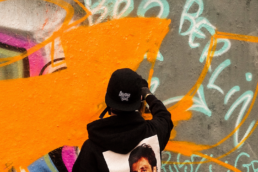 Jugendlicher mit Basecap besprüht Graffiti-Wand