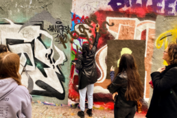 Jugenldiche sprayen an Wand mit Graffiti