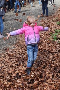 Kind spielt im Wald mit Laub